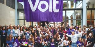 A group photo of women standing under a large purple Volt banner 