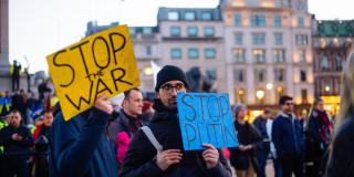 People hold "Stop War" / "Stop Putin" signs