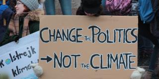 Person holds sign saying "Change the politics, not the climate"