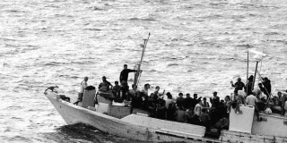 A flimsy boat with migrants in high sea.