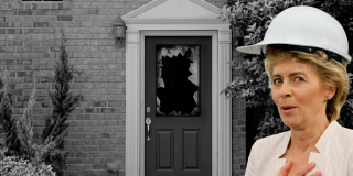 President von der Leyen wears a constructor hat in front of a house with a broken door
