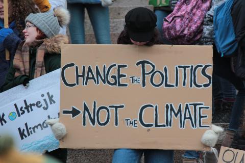 Person holds sign saying &quot;Change the politics, not the climate&quot;